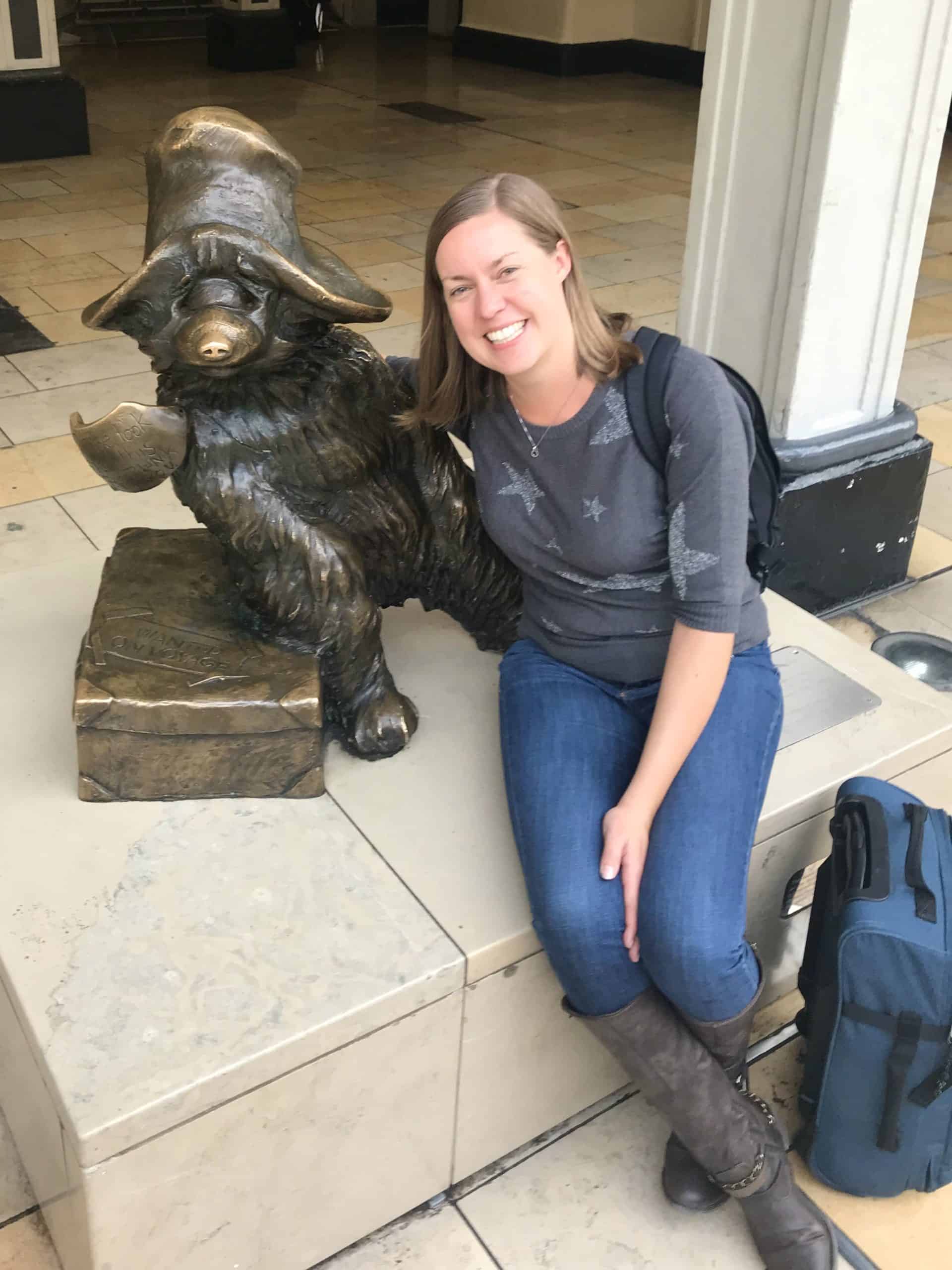 Joannda with her Eastpak carry on suitcase by Paddington Bear statue