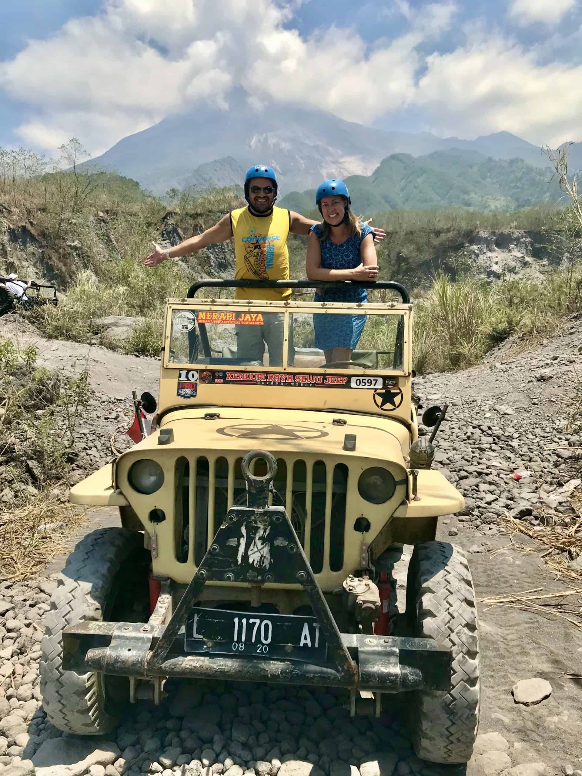 Omer and Joannda standing in the back of an open jeep in front of Mount Merapi