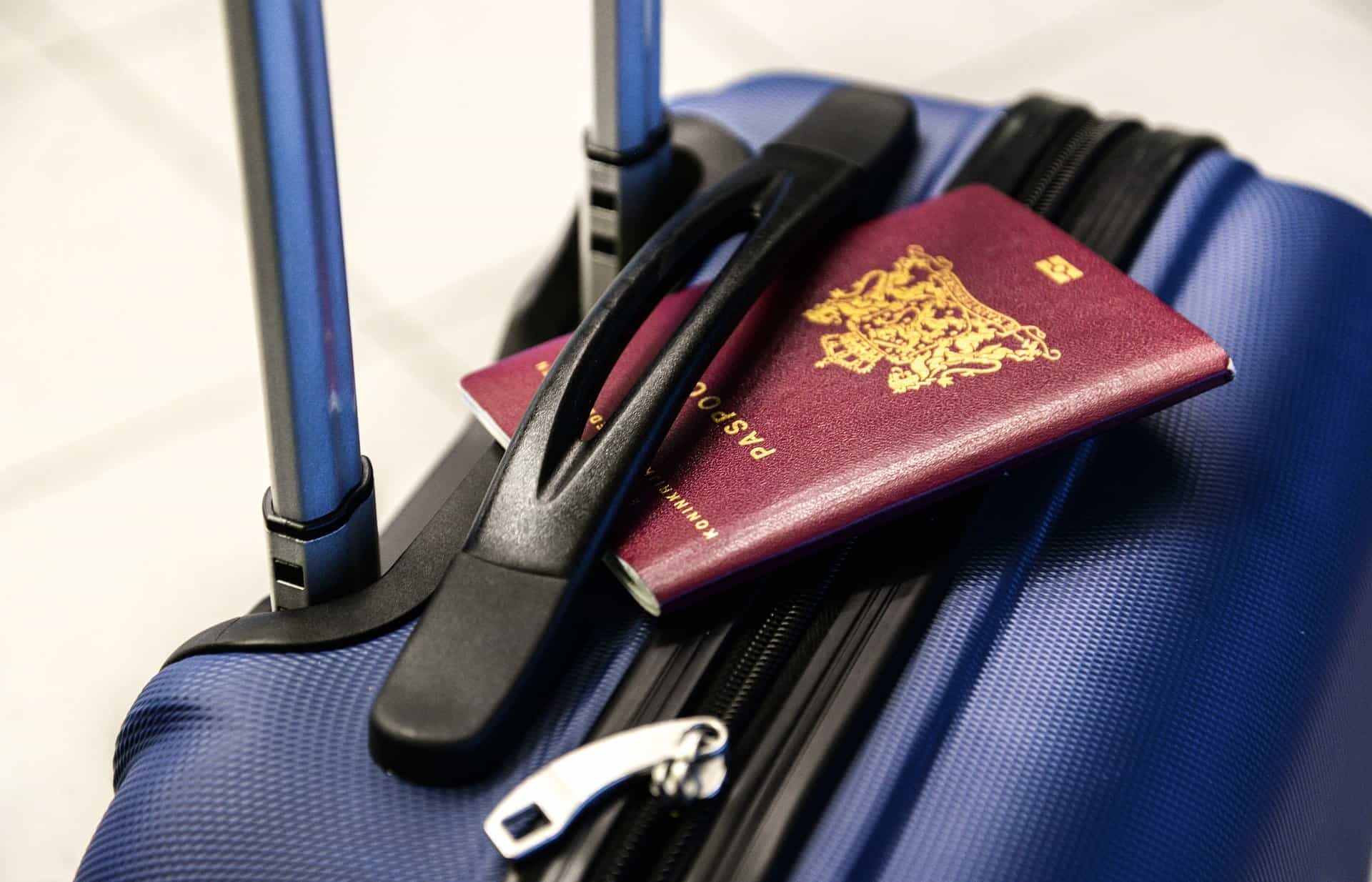 Dutch passport on top of a blue suitcase - make sure you have a current and valid passport before traveling