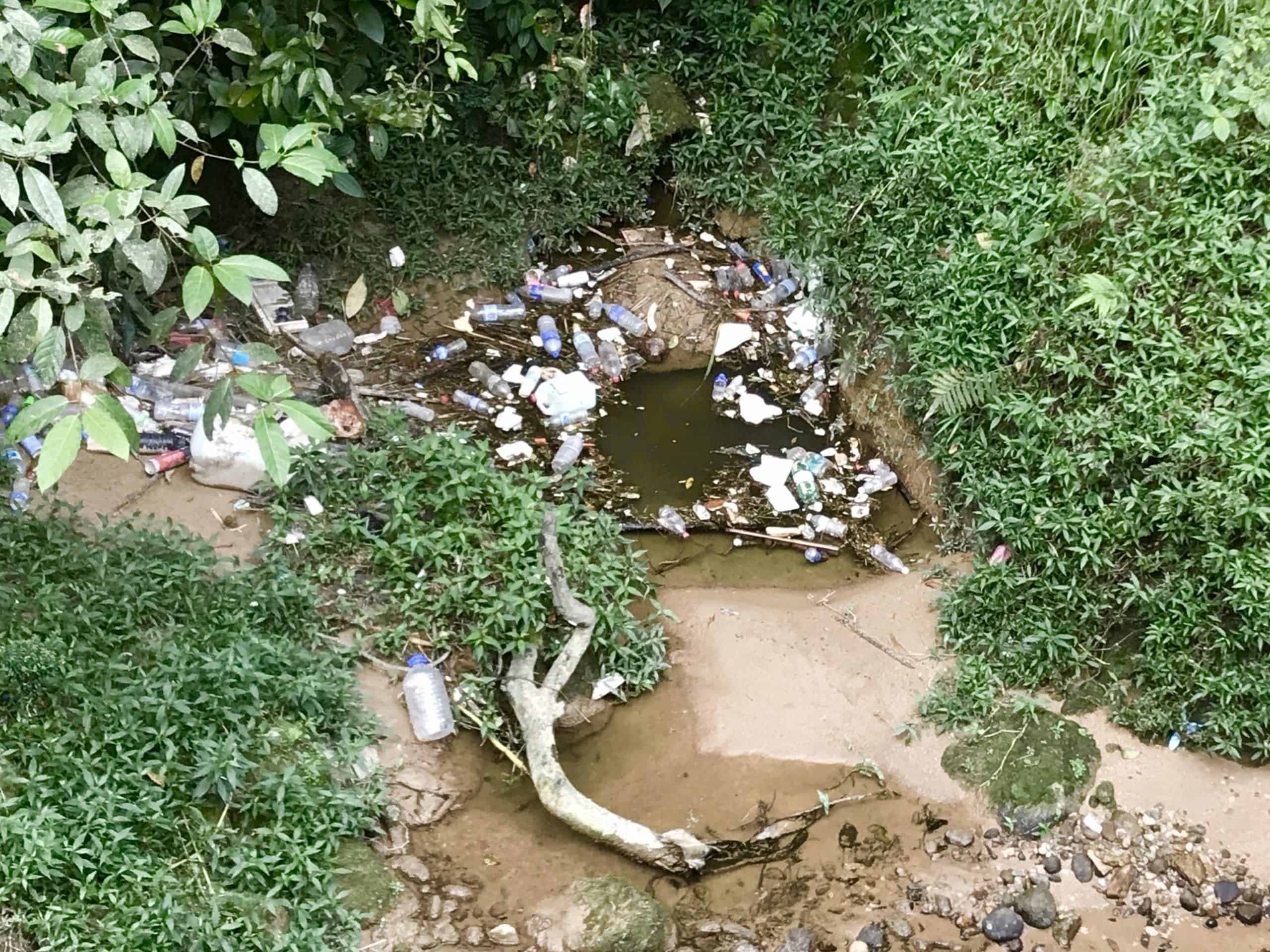 Piles of rubbish and plastic bottles in a stream